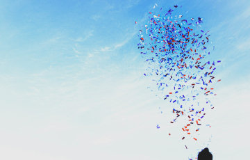 woman throwing confetti into blue sky