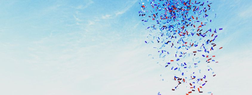 woman throwing confetti into blue sky