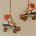 Two white and red roller skates hanging by red laces against a plain wall
