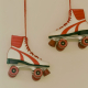 Two white and red roller skates hanging by red laces against a plain wall