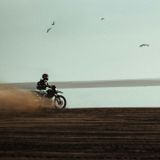 man riding on dirt bike near body of water