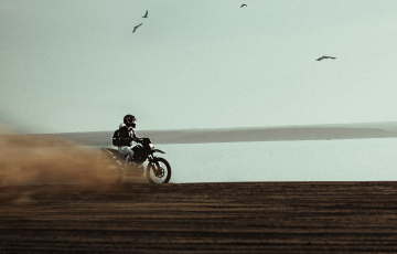 man riding on dirt bike near body of water
