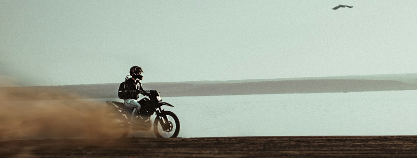 man riding on dirt bike near body of water