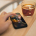 A person holding a cell phone next to a cup of coffee