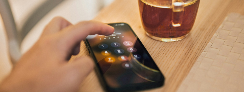 A person holding a cell phone next to a cup of coffee